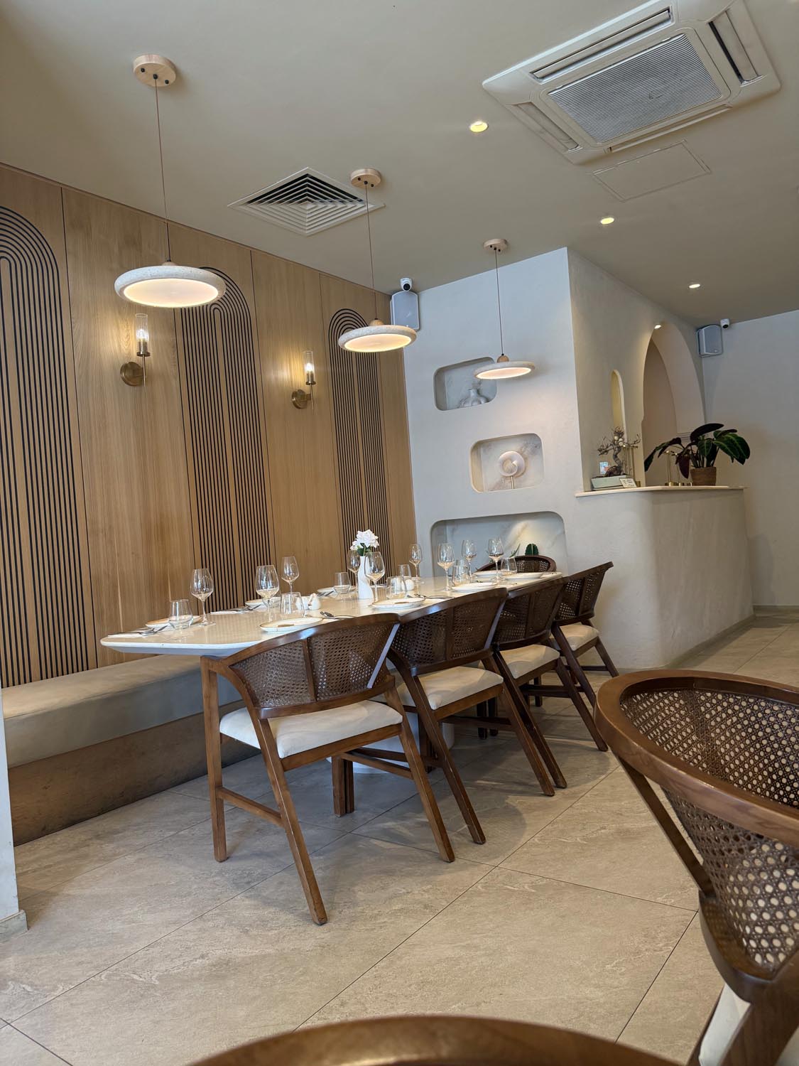 Long communal table against the pale oak feature wall with fine concentric arch linework