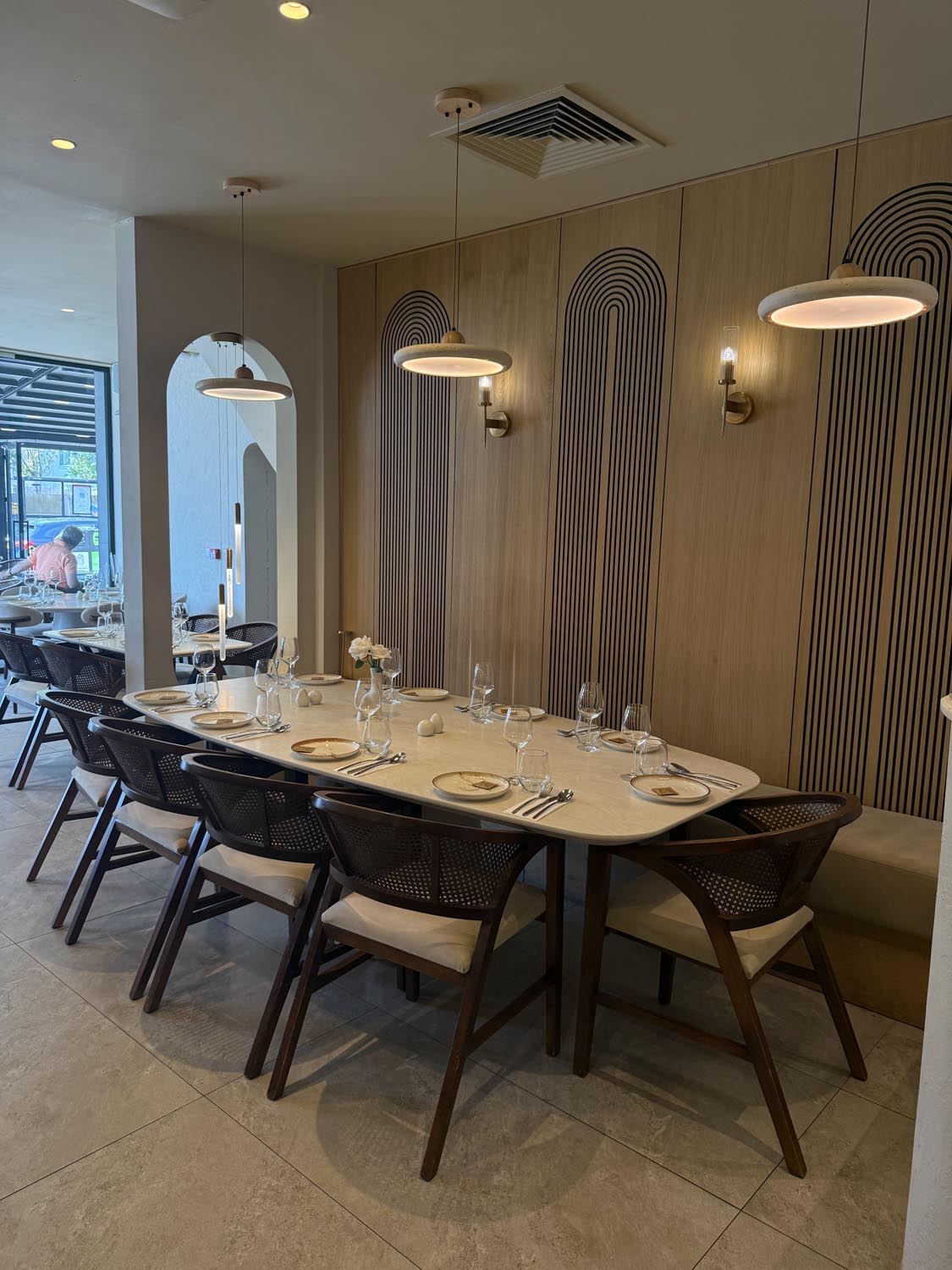 Ten-seat private dining table beneath disc pendants against the oak arch-panelled wall