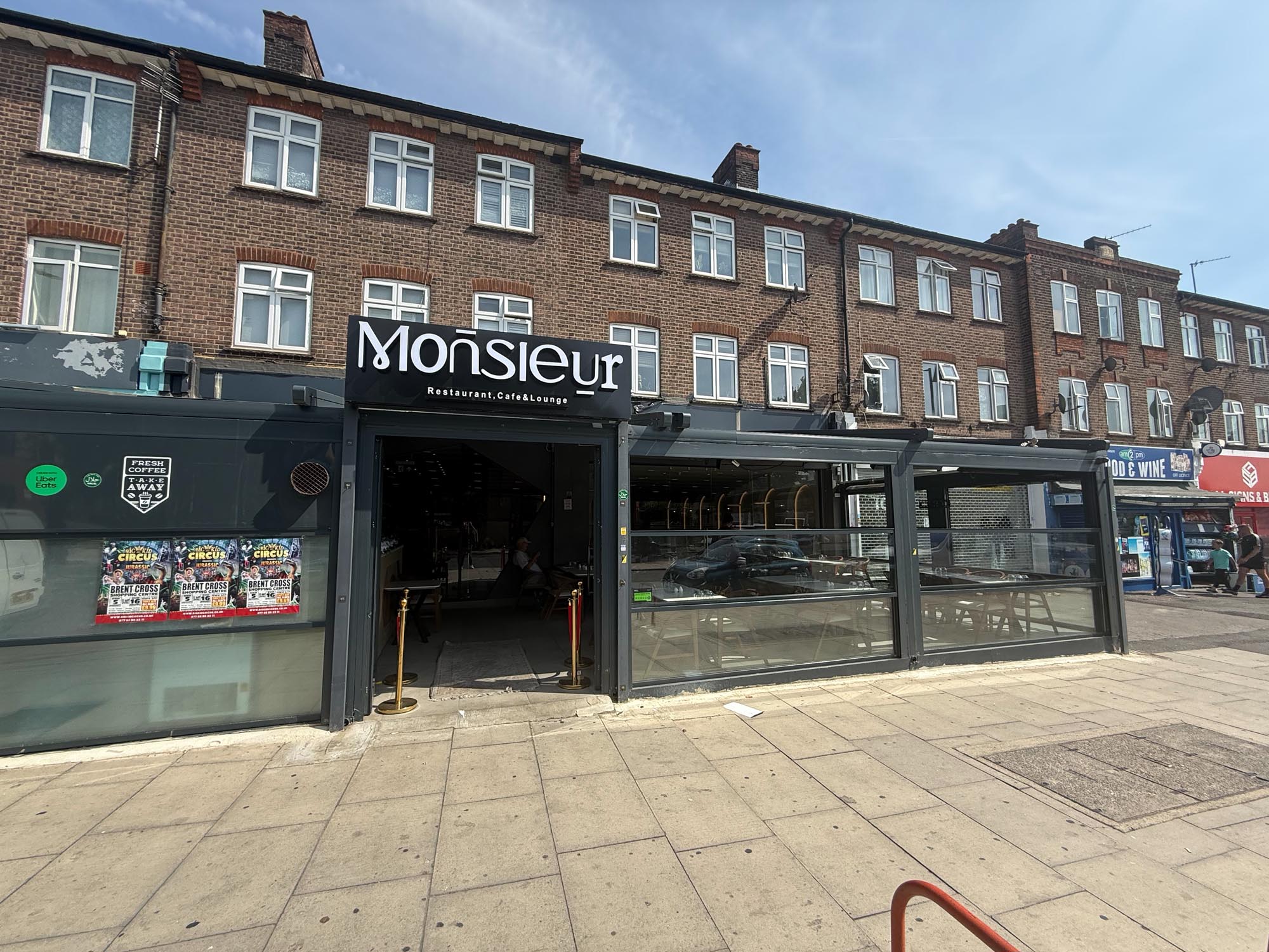 Monsieur Restaurant, Cafe & Lounge storefront on Woodhouse Road, North Finchley, with its black sign and glazed terrace